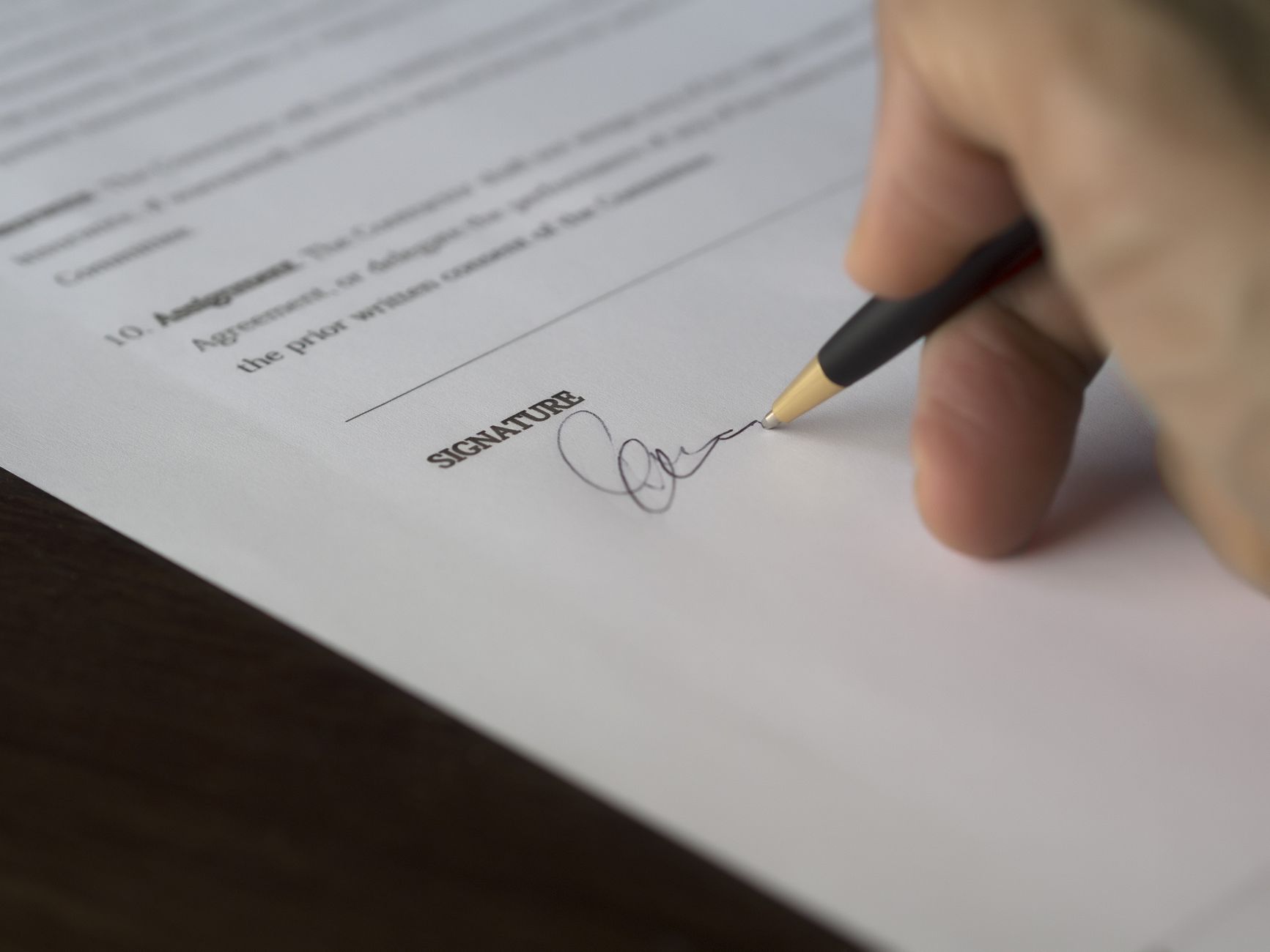 Person signing a paper contract on a desk
